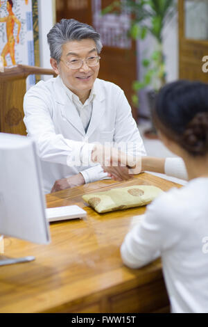 Senior medico cinesi stringono le mani con paziente Foto Stock
