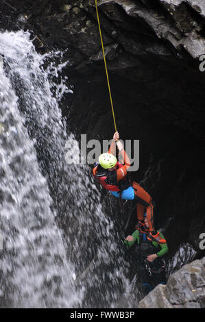 Un uomo di cordata lungo il lato di una cascata, in Perthshire, Highlands Scozzesi. Regno Unito. Foto Stock