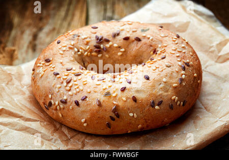 Bagel di mais con semi nel sacchetto di carta sul tavolo in legno Foto Stock