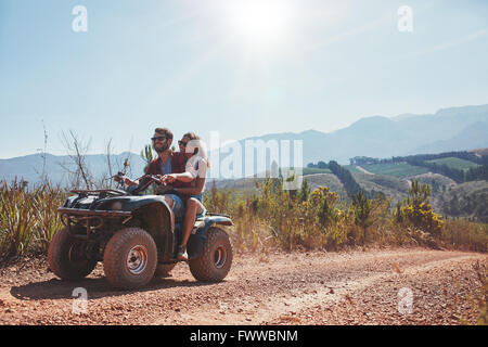 Amorevole coppia giovane godendo di una moto quad ride in campagna. Giovane a cavallo su un ATV. Foto Stock