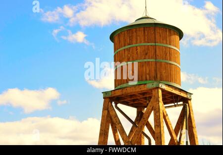 Una vista del legno di un water tower alto nel torbido cielo blu Foto Stock