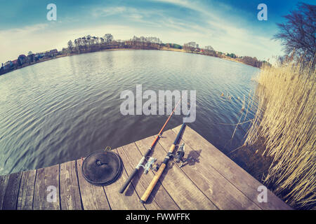 Vintage tonica obiettivo fisheye foto di due canne da pesca sul molo in legno. Foto Stock