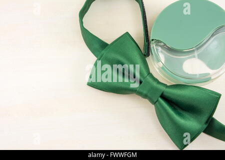 Green Bow tie e profumi su una tavola di legno Foto Stock