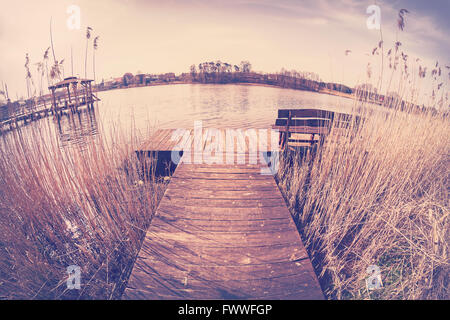 Vintage tonica obiettivo fisheye immagine di un molo in legno sul lago. Foto Stock