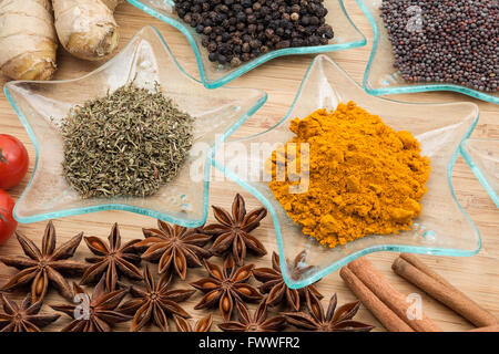 Spezie differenti su una tavola di legno con verdure fresche Foto Stock