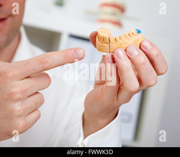 Dentista che mostra cast dentale nel suo ufficio Foto Stock