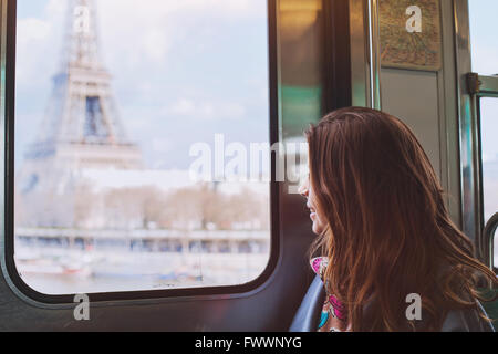 Per turisti in cerca della Torre Eiffel attraverso la finestra della metro di Parigi, sorridente ragazza visita in Francia Foto Stock