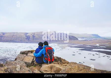 Paio di escursionisti di viaggio in Islanda, due backpackers godendo di vista del ghiacciaio e paesaggio di montagna Foto Stock