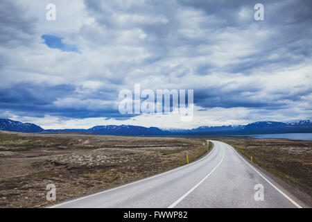 Sfondo di viaggio, bella strada asfaltata nel drammatico paesaggio di Islanda Foto Stock