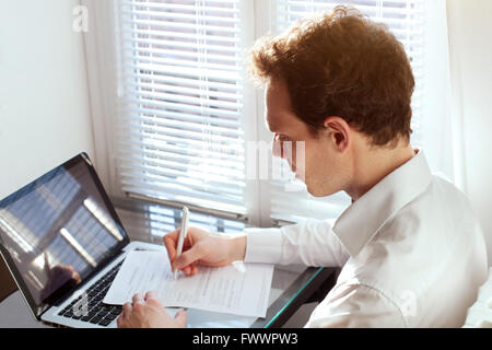 Imprenditore lavora con documenti, la lettura di un contratto o di riempimento sotto forma di imposta in ufficio vicino al computer Foto Stock