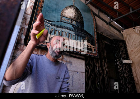 Un uomo palestinese siede di fronte ad un tappeto raffigurante la cupola della roccia nel quartiere palestinese di Silwan o Siloam situato sulle pendici appena a sud delle mura della Città Vecchia Gerusalemme Est Israele Foto Stock