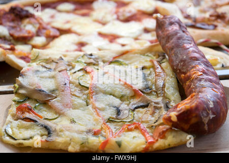 Pizza a cuneo con sottile salame piccante e zucchine e mozzarella Foto Stock