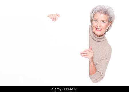 Senior donna con segno bianco davanti a uno sfondo bianco Foto Stock