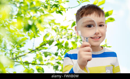 Happy little boy guardando attraverso la lente di ingrandimento Foto Stock