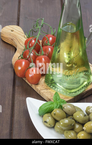 Ciotola bianco marinato con olive verdi viene collocato su una scrivania in legno. I pomodori sono giacenti su una scrivania di legno d'ulivo. Foto Stock