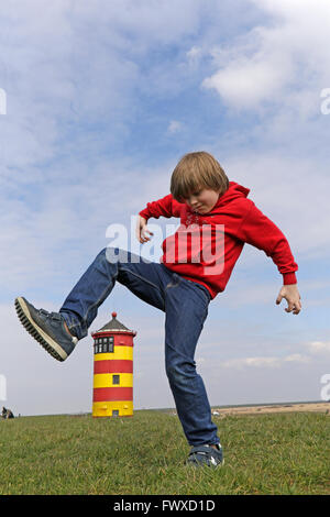 Ragazzo giovane a scavalcare Pilsum Lighthouse, East Friesland, Bassa Sassonia, Germania Foto Stock