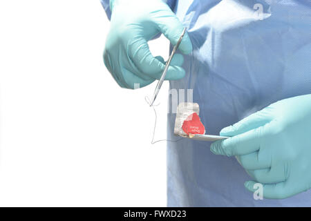 In sala operatoria il tecnico prepara la sutura per l'uso con il supporto dell'ago. Foto Stock