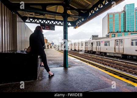 Astoria di New York - 7 Aprile 2016 - Metropolitana commuter in attesa sulla piattaforma di una metropolitana sopraelevata piattaforma nel Queens. ©Stacy Rosenstock Walsh/ Alamy Foto Stock