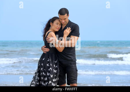 Felice coppia romantica sulla spiaggia.giovani felici interracial giovane sulla spiaggia che abbraccia ogni altro. Donna asiatica,uomo caucasico Foto Stock