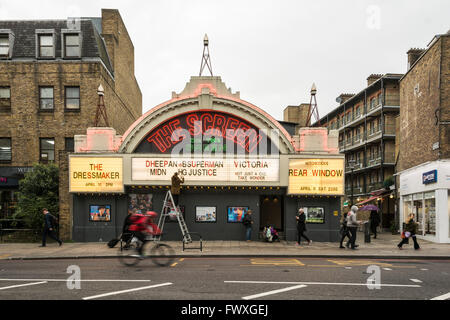 Un uomo su una scala diplays odierna elenchi nella parte anteriore dello schermo sul verde del cinema su Upper Street, Islington, London, Regno Unito Foto Stock