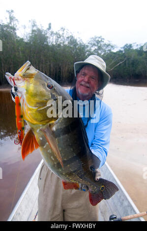 Un pescatore che solleva un gigante peacock bass catturati su un chopper-spina tipo tinto in acque della laguna off il colombiano Cano Bocon (fiume). Foto Stock