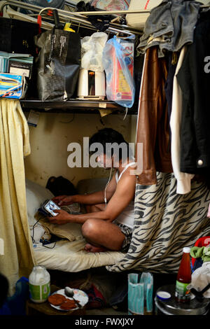 Il Qatar Doha, complesso industriale al di fuori della città, alloggiamento camp per il lavoratore migrante , sei lavoratore filippino condividono un 10 mq di camera, lavoratore Noel comunica da Samsung tablet con la sua famiglia a Manila Foto Stock