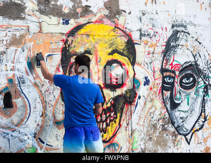 Graffiti artist la spruzzatura su un vecchio graffiti sul muro in Spagna Foto Stock