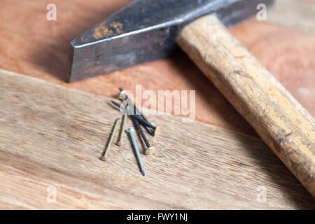 Martello con chiodi su sfondo di legno Foto Stock