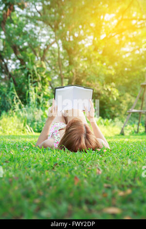 Bella asiatica giovane donna leggendo nel parco Foto Stock