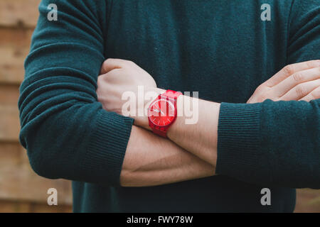 Mens moda, vicino fino alle mani dei maschi di indossare orologi rosso e verde pullover, concetto di stile Foto Stock