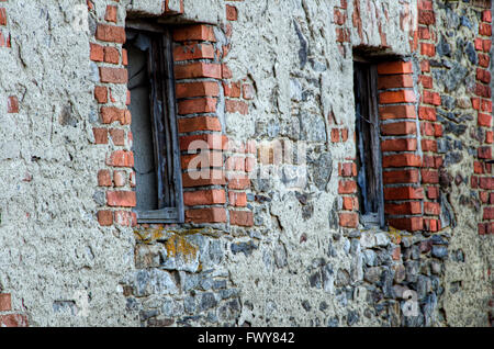 Due finestre in pietra vecchio muro di mattoni. Foto Stock