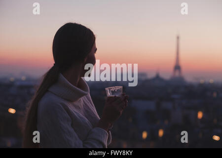 La donna gode di splendida vista panoramica di Parigi con la tazza di caffè, serata intima in cafe Foto Stock