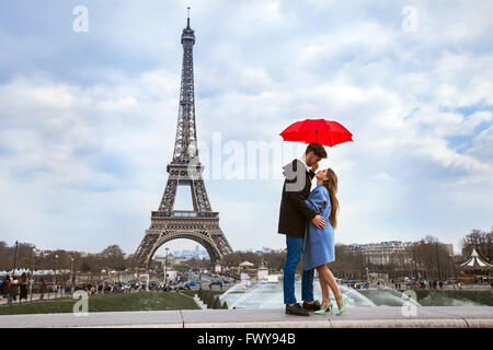 Bella giovane con ombrellone vicino alla Torre Eiffel, luna di miele a Parigi, romantico momento Foto Stock