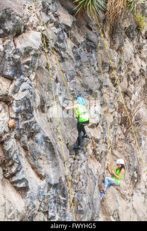 Banos, Ecuador - 30 Novembre 2014: la sfida di basalto del Tungurahua, giovanile ispanica scalatori del team di eseguire un esercizio arrampicata Foto Stock