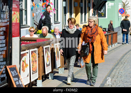 Simrishamn, Svezia - Aprile 1, 2016: due senior donne a piedi da un ristorante, parlando di ogni altro. Persone reali nella vita di tutti i giorni. Foto Stock