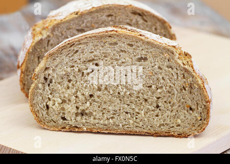 La metà di un pane rustico sul pannello di legno Foto Stock