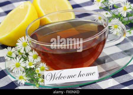 Benvenuti a casa carta con la tazza di tè e i fiori di camomilla Foto Stock