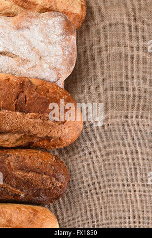 Cinque diverse forme di pane su una tavola di legno con copia spazio. Formato verticale. Foto Stock