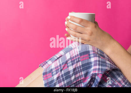 Donna in pijama avente una mattina tazza di caffè Foto Stock