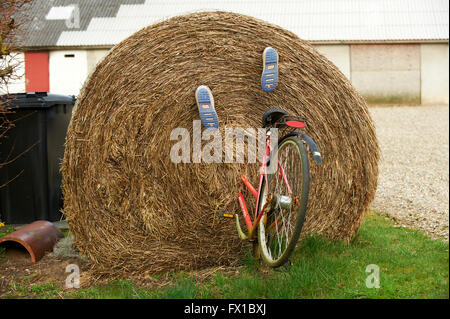 Grandi balle di paglia con bicicletta e stivali di gomma montato a guardare come se la persona che guida esso è scomparso nella balla Foto Stock