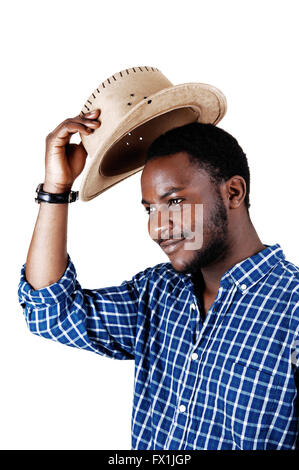 Un bel uomo nero in una maglietta blu sollevando il suo cappello da cowboy e sorridente isolato per sfondo bianco. Foto Stock