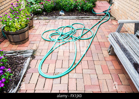 Un tubo flessibile da giardino in un cortile a sinistra in un mucchio disordinato. Oklahoma City, Oklahoma, Stati Uniti d'America. Foto Stock