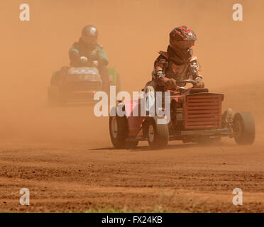 Due uomini che indossano caschi la guida motofalciatrici emergente dalla nube di polvere rossa sulla via insolito Australian motor racing sport Foto Stock