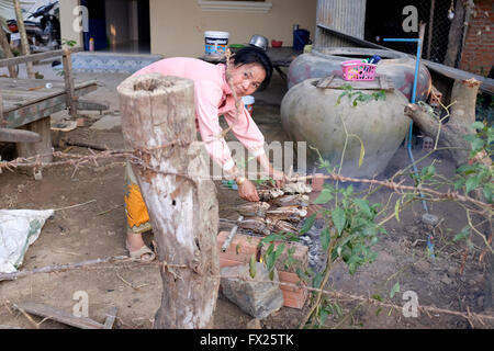 La donna pesce cottura nel villaggio cambogiano e cattura il fotografo Foto Stock