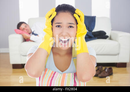 Immagine composita di distressed donna indossando grembiuli e guanti di gomma Foto Stock