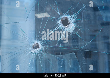 Due fori di proiettile in finestre di vetro Foto Stock