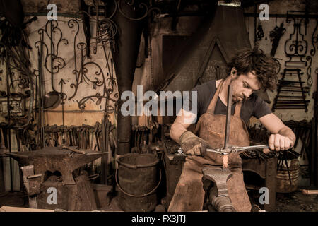 Ironworker forgiatura del ferro caldo in officina Foto Stock