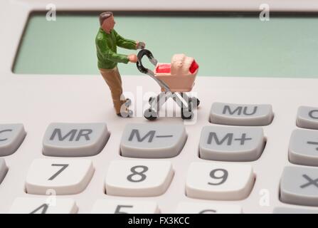 Un unico maschio statuetta in miniatura genitore spingendo una carrozzina su tasti della calcolatrice Foto Stock