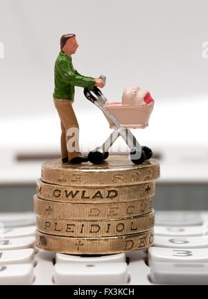 Un unico maschio statuetta in miniatura genitore con una carrozzina permanente sulla libbra di monete e di una calcolatrice Foto Stock