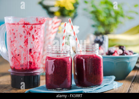 Fresco frullato blended, nella soleggiata cucina sulla tabella di agriturismo. Lo spazio negativo per il testo, gli ingredienti e la frutta fresca in backgrou Foto Stock